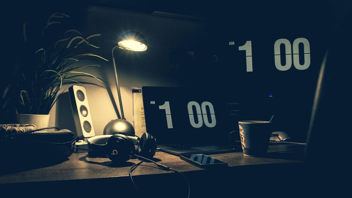 Stagiaire travaillant tard dans un bureau avec horloge visible